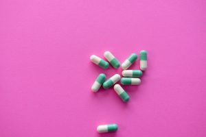 white and blue medication pill on pink textile